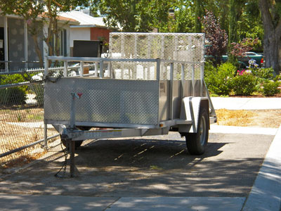 Silver metal trailer and hitch in the driveway of a residential home provided by ALPCO Recycling in Macedon, NY