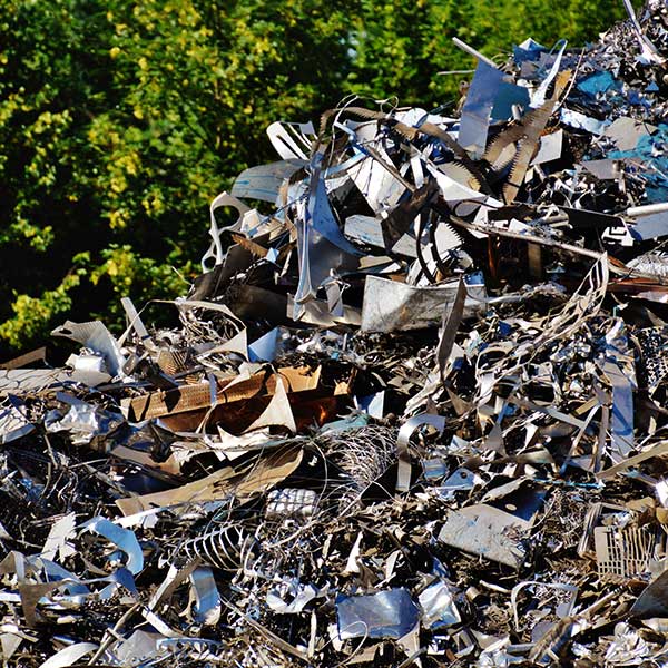 Discarded metal scraps in a large pile next to some trees recycled by ALPCO Recycling in Macedon, NY